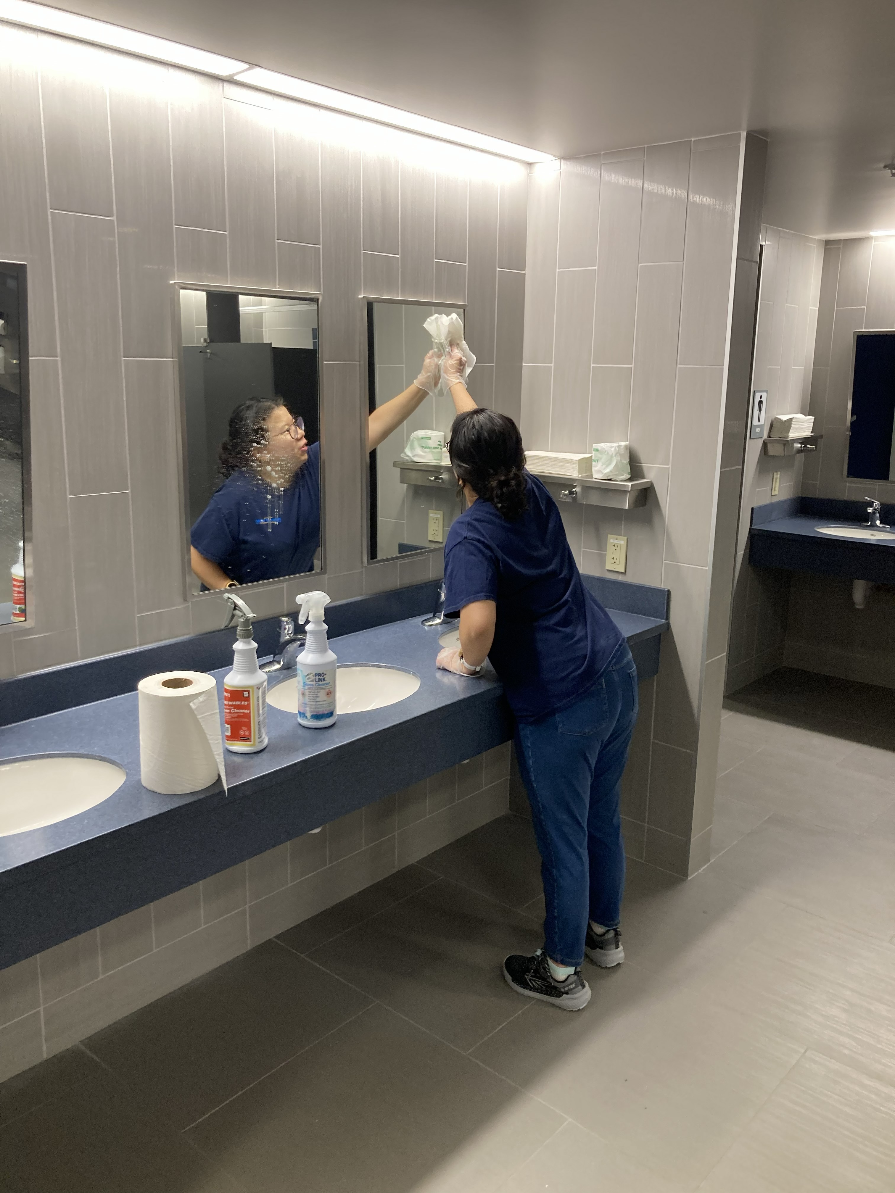 A janitorial team member cleaning a mirror