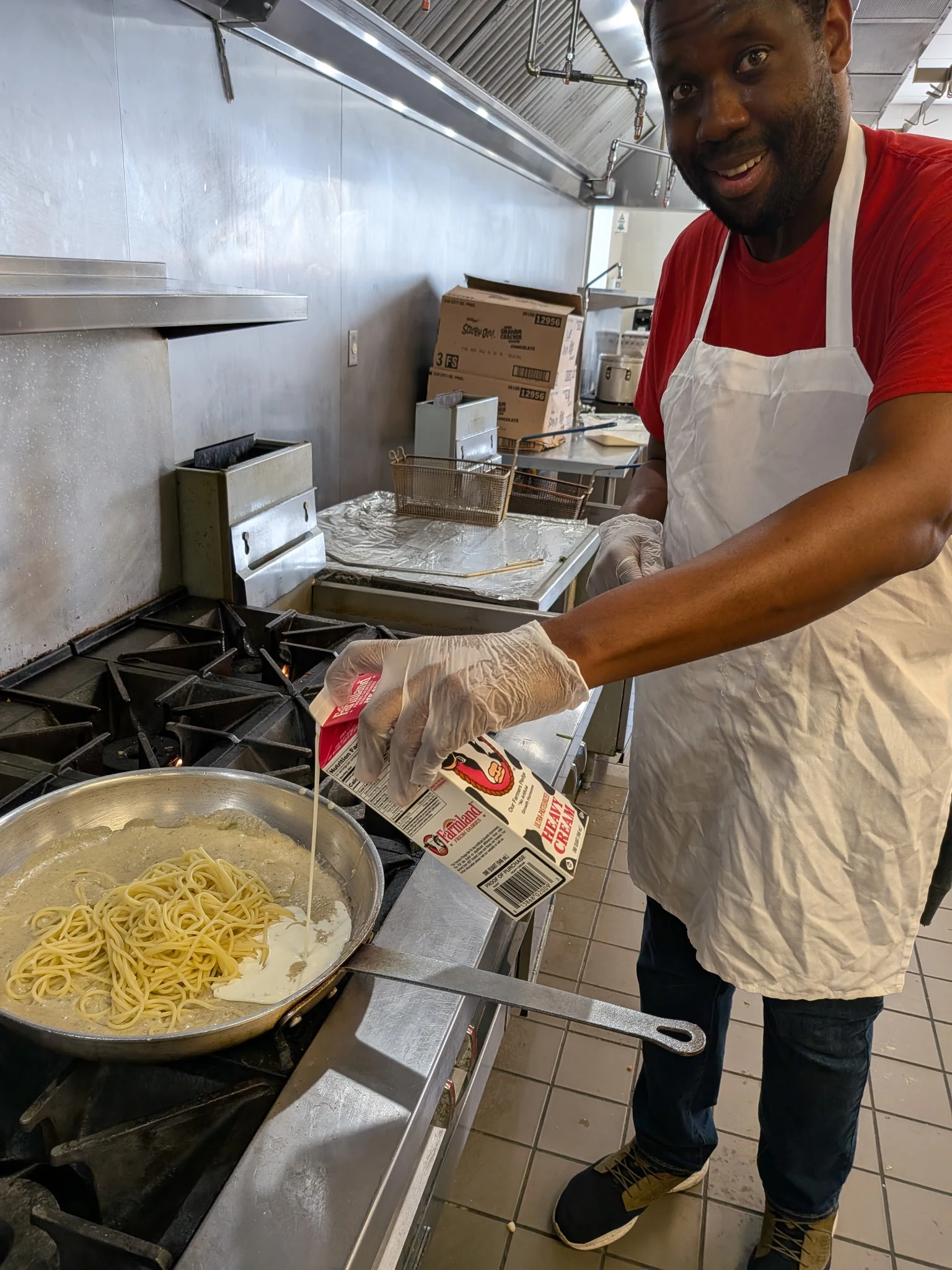 A catering team member preparing pasta in the Friendship House kitchen