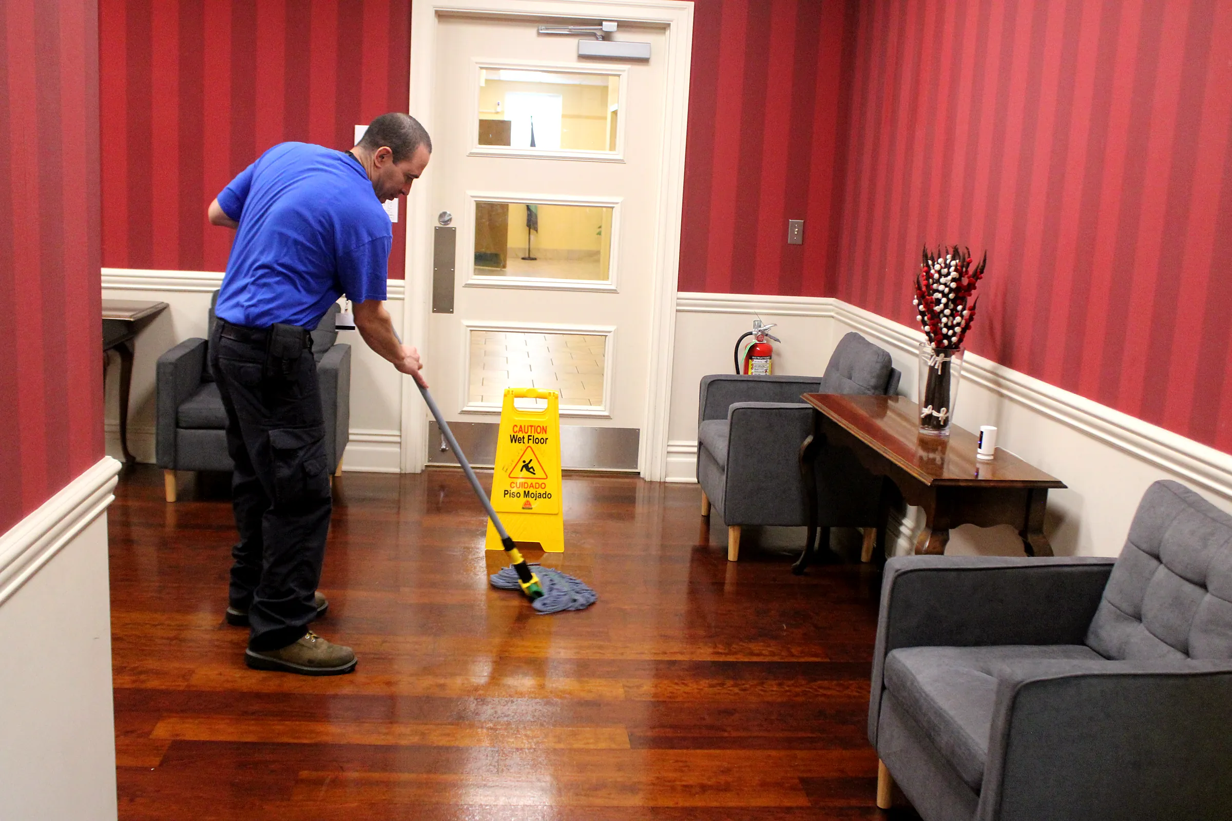 A janitorial team member mopping a reception area