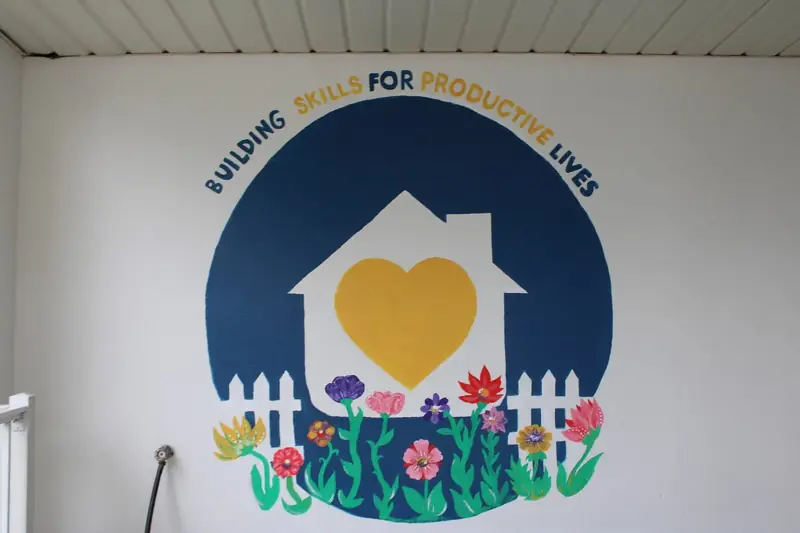 The completed Friendship House mural features a yellow heart surrounded by flowers.