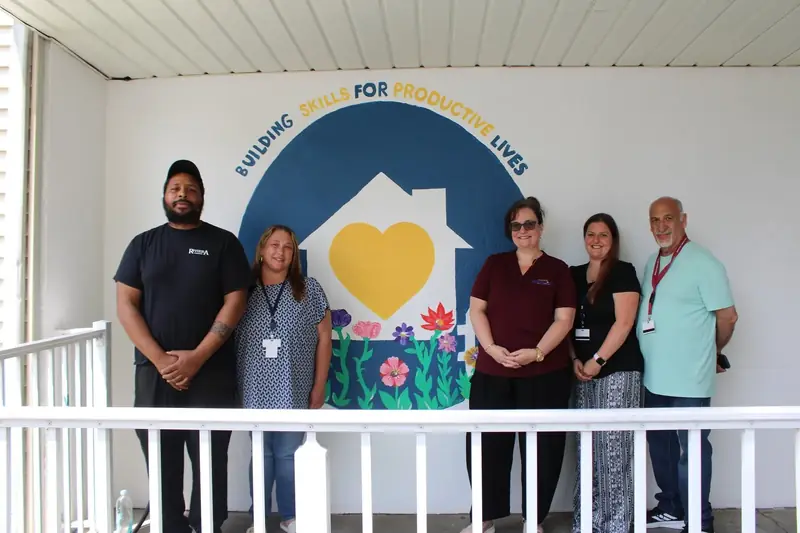 Friendship House team members stand together in front of the completed mural.