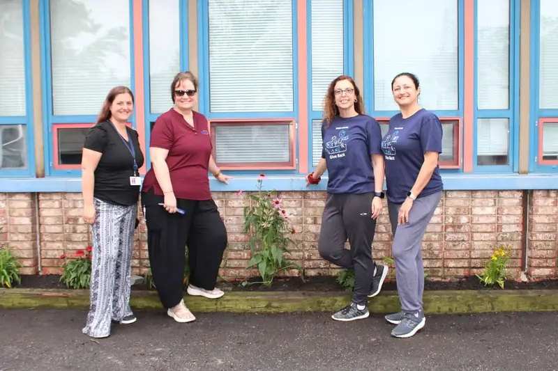 Friendship House staff and volunteers stand together beside the newly planted garden.