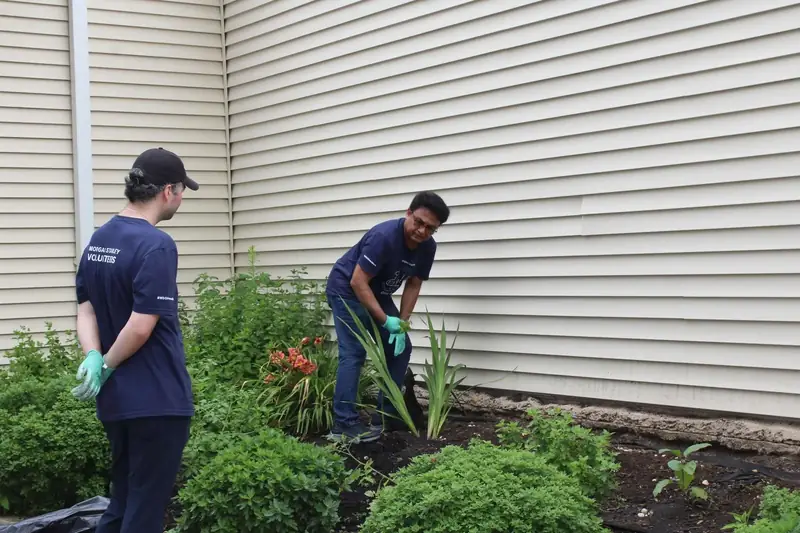 Two volunteers plant flowers in a garden bed at Friendship House.