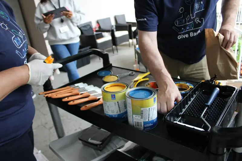 Volunteers prepare blue and yellow paint and brushes for a community project.