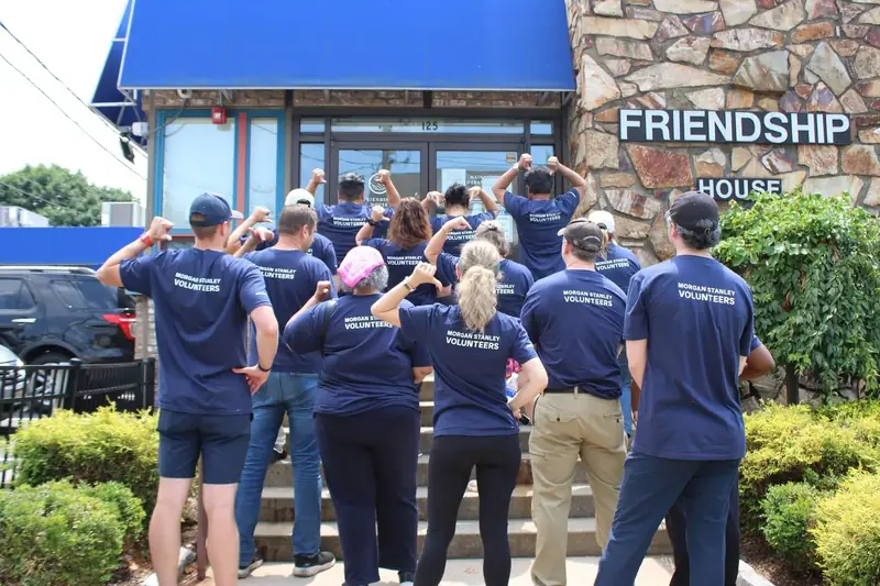 A large group of volunteers celebrates outside Friendship House.
