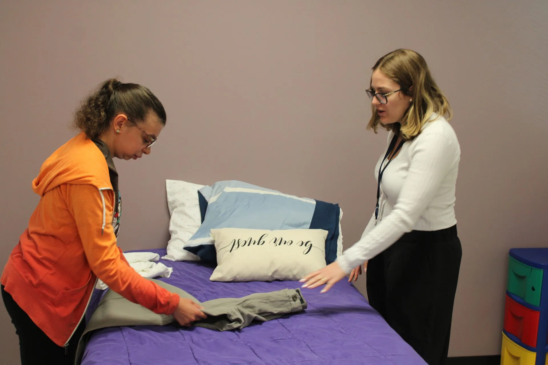 A participant folding clothes with staff support