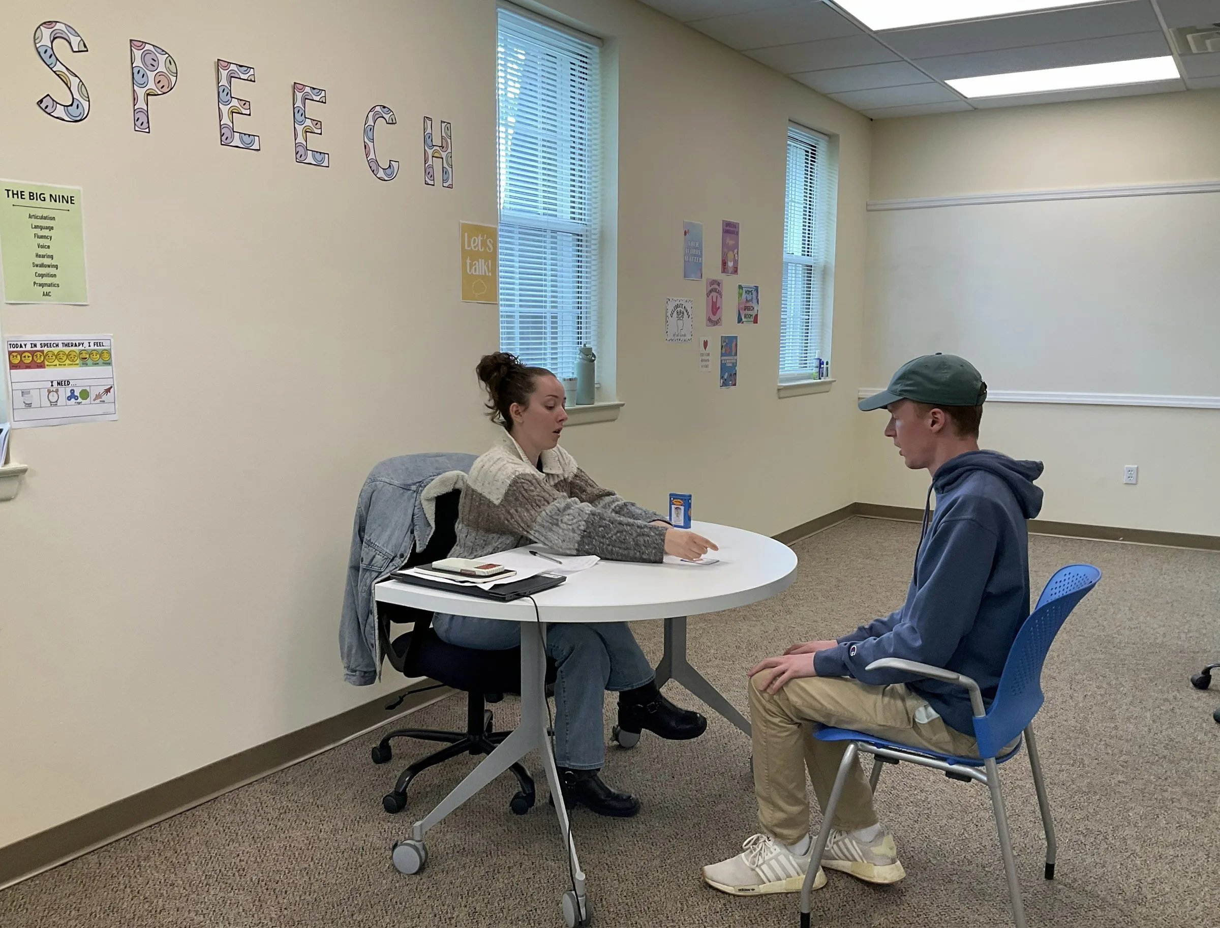 A participant and staff member working together at a table in the speech room