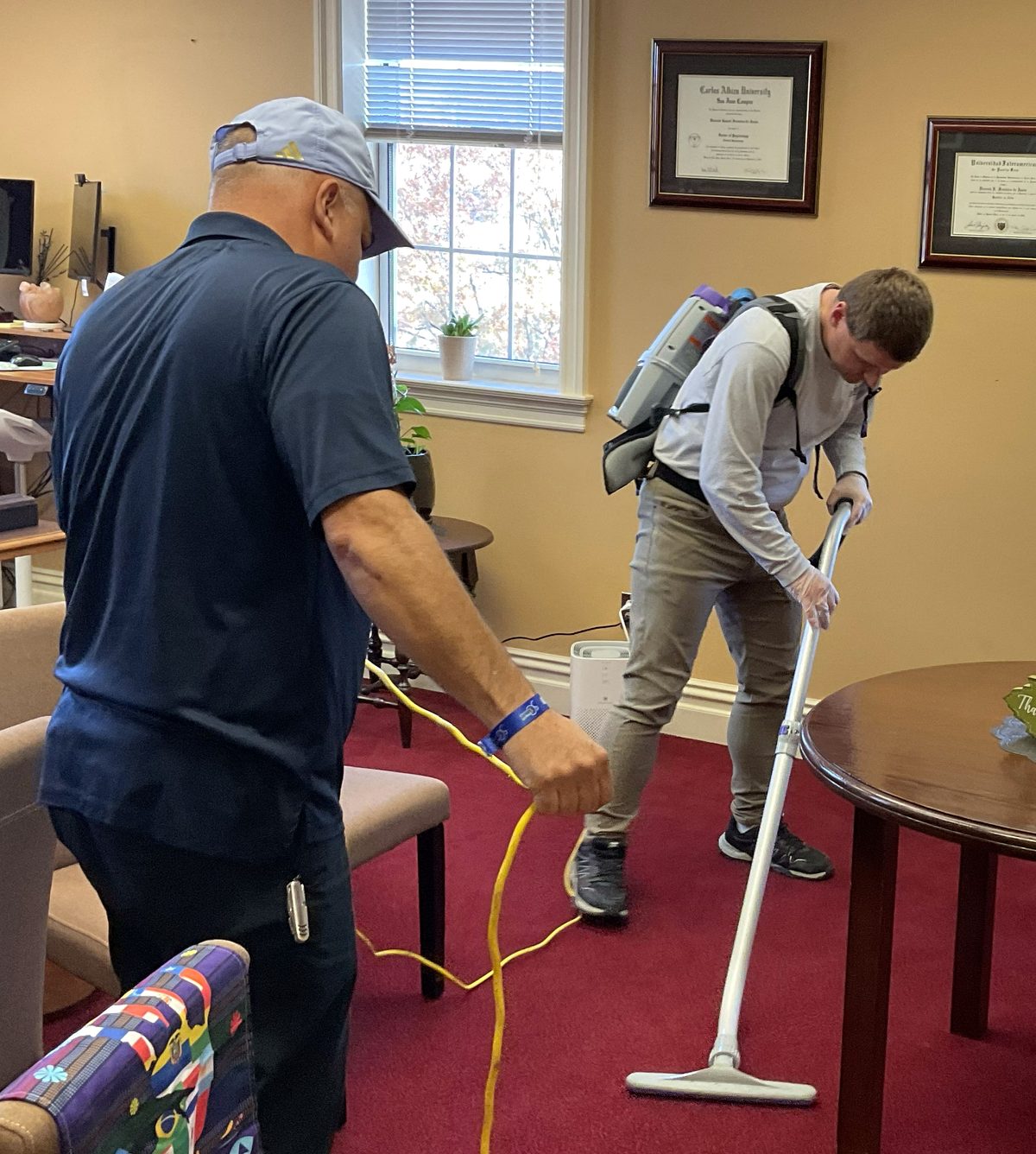 An Extended Employment participant practicing vacuuming with staff guidance