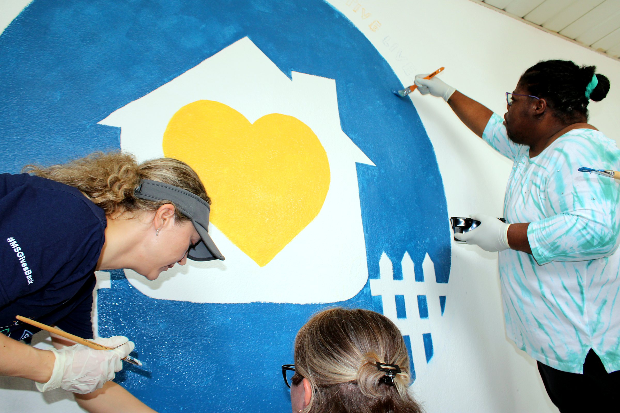 A Partial Care member and community volunteers painting a mural